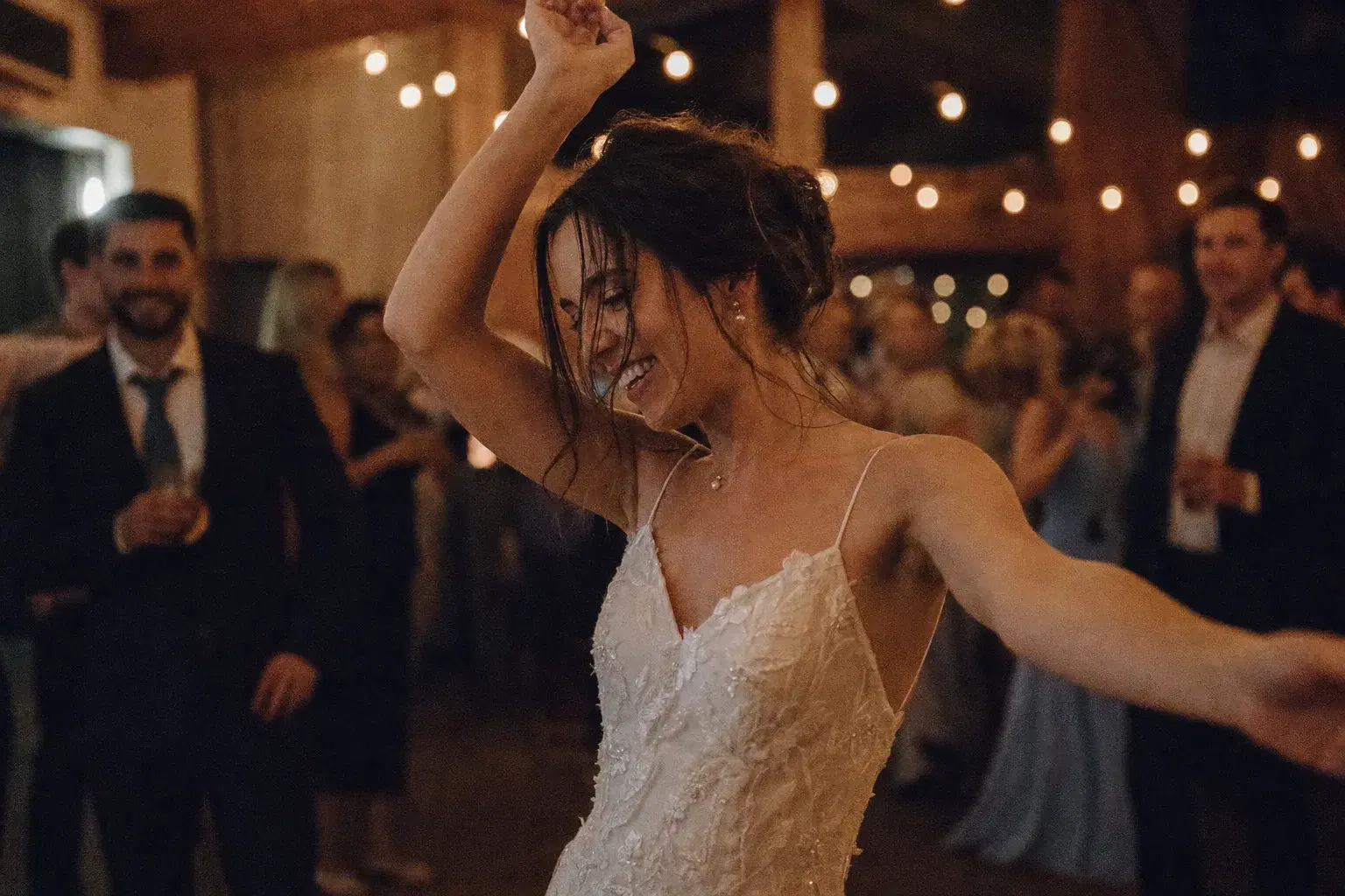 A guest dancing under warm lights at a dim wedding reception photographed with natural grain.