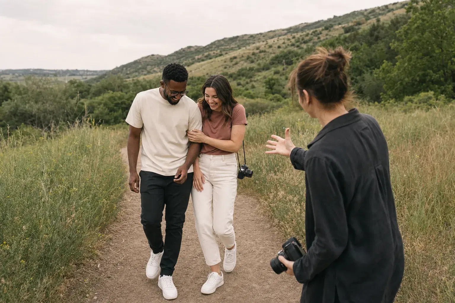 A photographer directing a couple as they walk and laugh together outdoors.